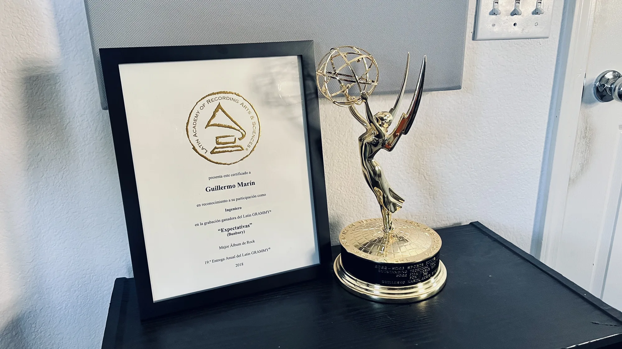 Sports Emmy statuette beside Guillermo Marin's Latin Grammy certificate for Bunbury's Expectativas