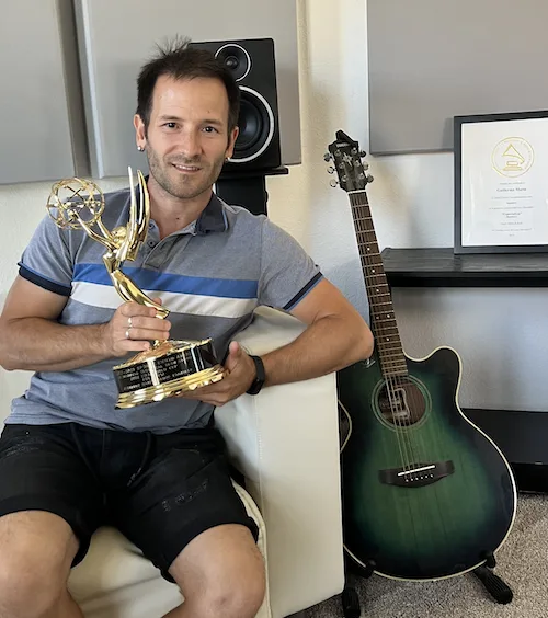 Guillermo holding a Sports Emmy award in his studio